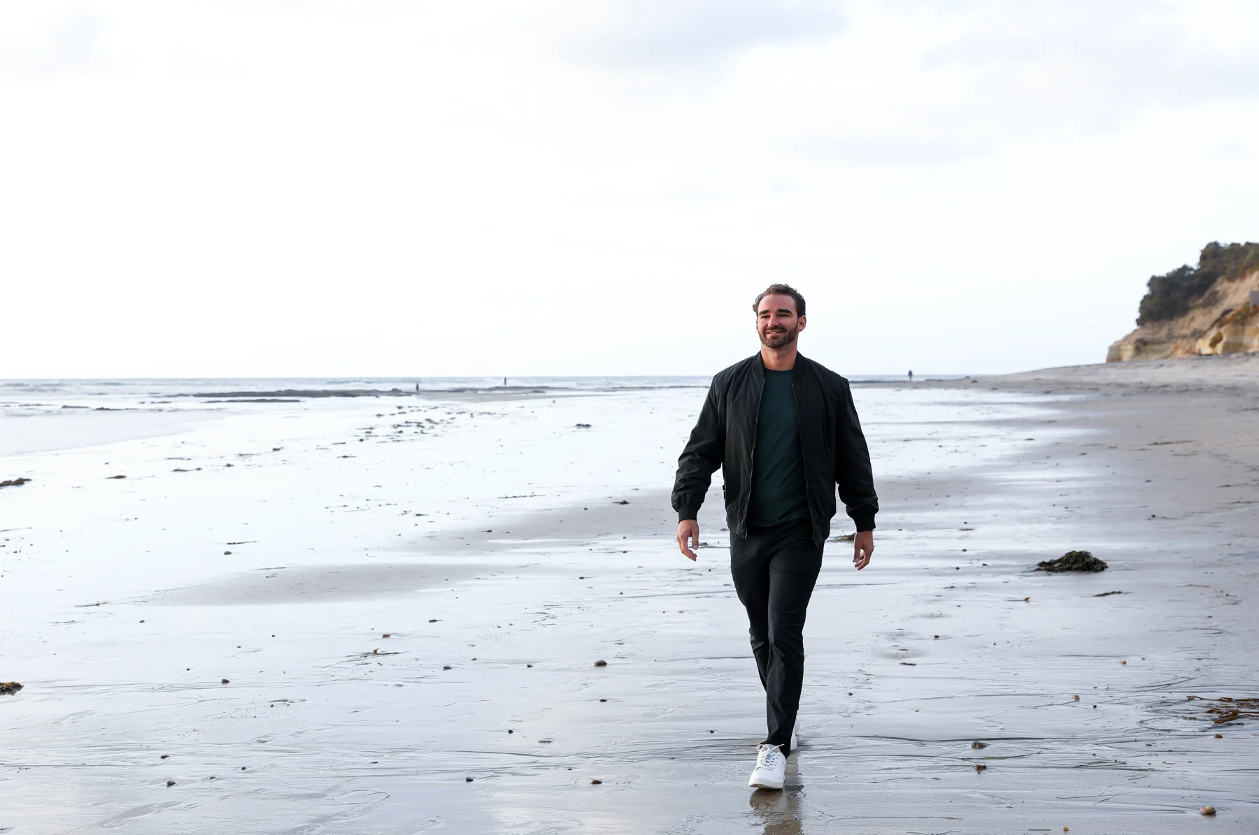 Joshua walking barefoot along the shore in San Diego